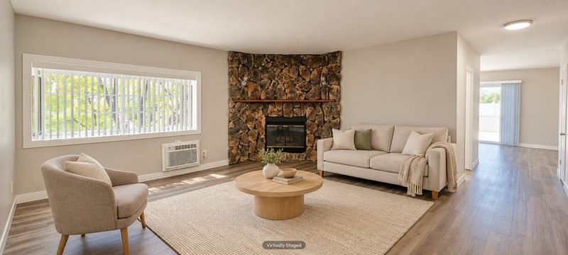Unit D living room with a stone fireplace, virtually staged