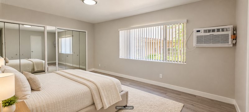 Unit D bedroom with mirrored closet doors, virtually staged
